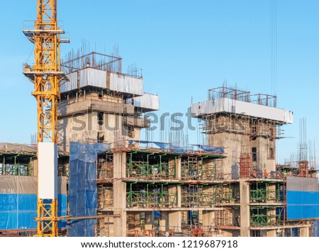 Condominium construction site with cranes and building under construction against blue sky.