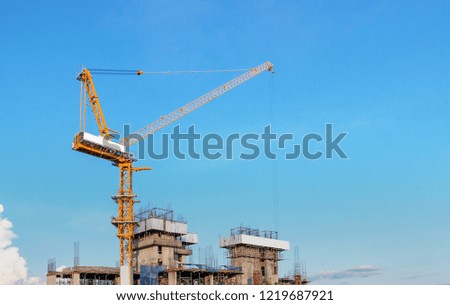Crane and building under construction against blue sky. Condominium construction site with cranes