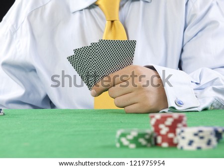 card player with yellow tie  gambling casino chips on green felt background selective focus