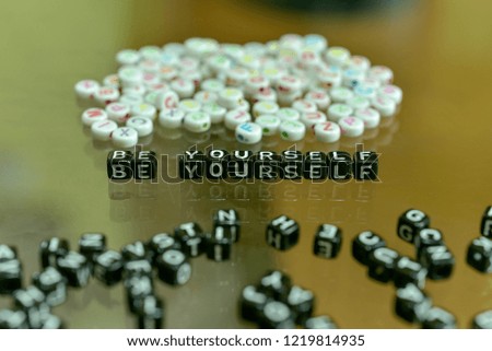 BE  YOURSELF  written with Acrylic Black cube with white Alphabet Beads on the Glass Background