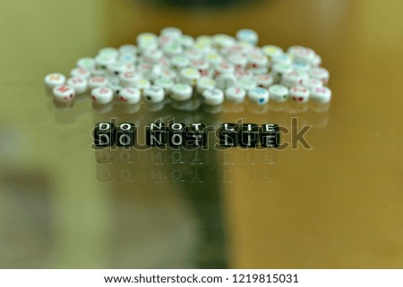 DO NOT LIE  written with Acrylic Black cube with white Alphabet Beads on the Glass Background