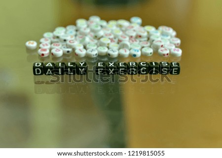 DAILY EXERCISE  written with Acrylic Black cube with white Alphabet Beads on the Glass Background