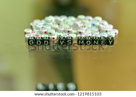 GOD VS MONEY  written with Acrylic Black cube with white Alphabet Beads on the Glass Background