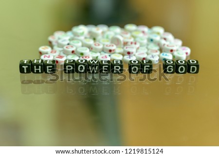 THE POWER OF GOD written with Acrylic Black cube with white Alphabet Beads on the Glass Background