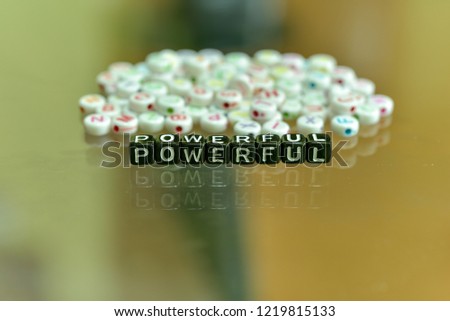 POWERFUL written with Acrylic Black cube with white Alphabet Beads on the Glass Background