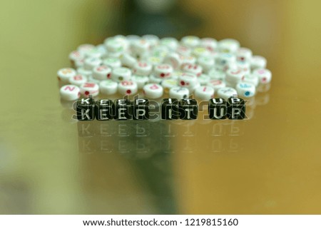 KEEP IT UP  written with Acrylic Black cube with white Alphabet Beads on the Glass Background