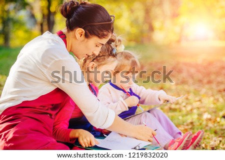 Happy mother, and two kids are painting in the park. The concept of a happy family.