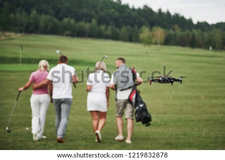 Group of stylish friends on the golf course learn to play a new game. Shooting is conducted from the quadcopter drone