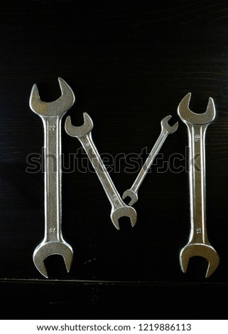Letters of the alphabet that make up with metal wrenches and wooden background, ideal for composing names and brands.