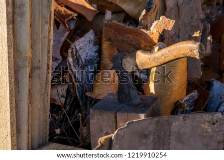 The axe stuck in a log in the yard about a woodpile on the street