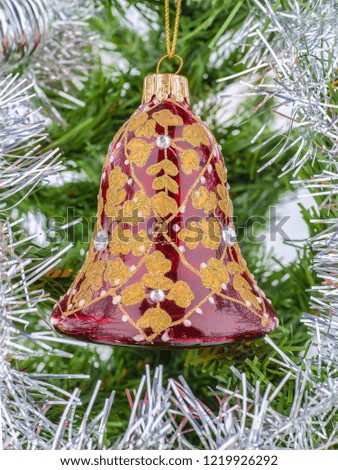 Christmas tree Toy in the form of a bell on a green tree and artificial silver rain. Decoration and symbol of Christmas holidays.