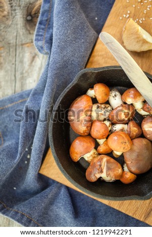Raw mushrooms, white and brown on a wooden table with a frying pan