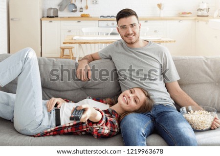 Young smiling couple watching tv on couch at home