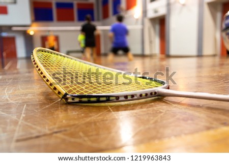 Broken badminton racquet rim with badminton court as background