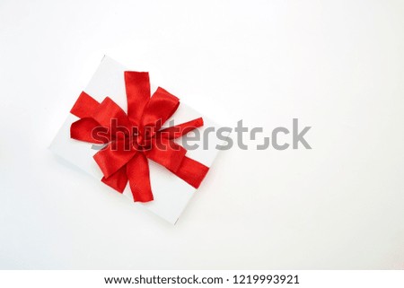 single white textured gift box with red ribbon bow on white background