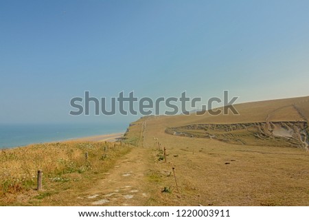 Hiking trail along a field and cliffs on the French Northe sea coast, with blue sea and sky 
