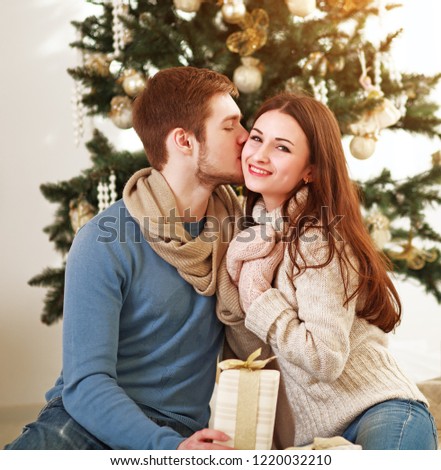 Young family couple in love at home at Christmas on the background of New Year tree give gifts