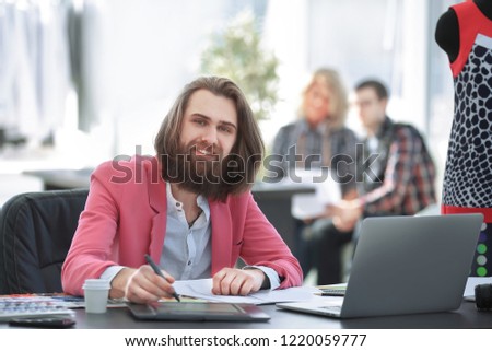 smiling fashion Designer at the table in a modern Studio