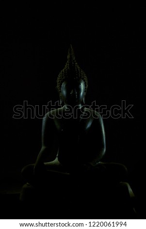 Buddha image on black background, low key style.