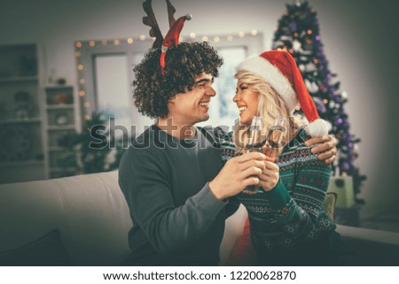Young romantic couple hugging and celebrating Christmas at home, they are having fun and toasting with beer. Selective focus.
