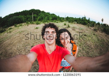 A man and a woman make selfie. Lovers walk in nature. Couple against the background of mountains.