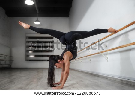The classic ballet dancer posing split at ballet barre on studio background. 