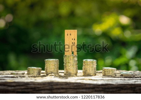 Wood house model and row of coin money on wood table with blur green leaves nature background, Real Estate market, Trading Estate, Mortgage Concepts