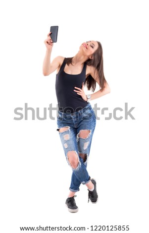 Cool energetic young girl taking selfie photo with mobile phone posing and smiling. Full body isolated on white background. 
