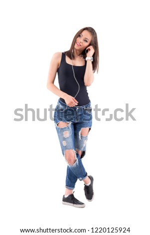 Cool trendy girl relaxing while listening to music on mobile phone earphones looking away. Full body isolated on white background. 