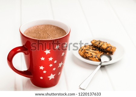 Hot cocoa in a red mug and saucer with cookies