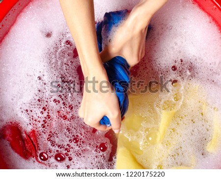 Women washing color clothes in basin enemale powdered detergent, top view