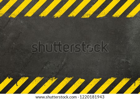 Dark grey oncrete weathered wall background with yellow painted grunge hazard sign stripes and copy space