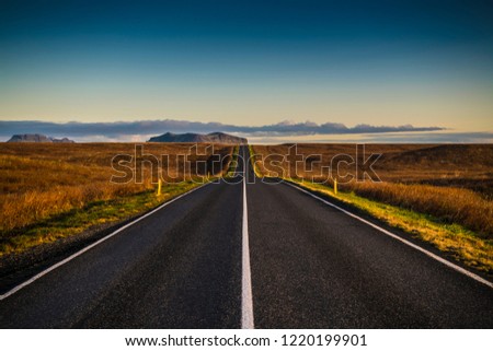 A road leading to distance at fine afternoon with mountains in the background in Iceland Royalty-Free Stock Photo #1220199901