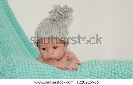 4 weeks old newborn baby boy with gray hat on green blanket copy space