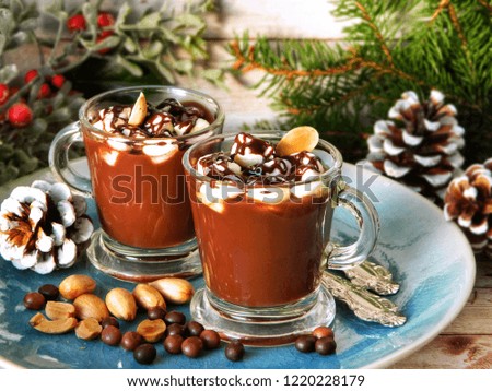 Hot chocolate in glass cups on a blue platter and Christmas decorations.