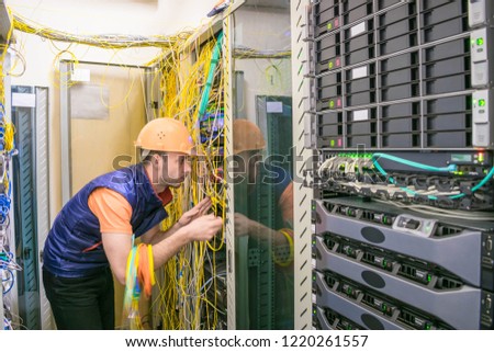 Professional internet campaign worker serves a rack with a central route. Engineer works with computer switching equipment. Technician restores Internet connection in the server room of  data center.