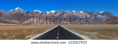 Panorama of landscape view of Tibet. Long & straight road ahead with high mountain range in front in the distance