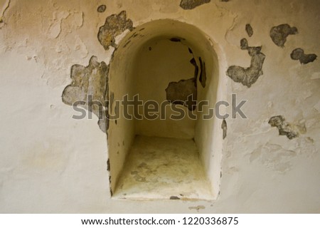 A small narrow recess, a niche with an arch on an old ancient stone white thick concrete wall in an old castle. The background.