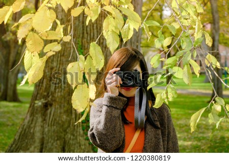 Traveler Woman taking Photography with her Camera in Park on Autumn Sunny Day