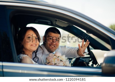 Bride and groom are looking from the windows of the car