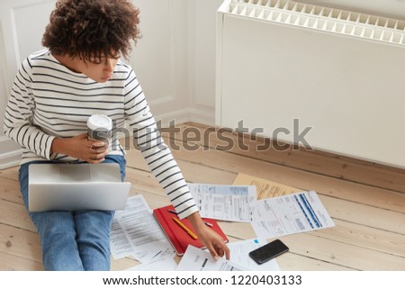 Top view of busy black lawyer checks important details of business contract, thinks on creative solutions, has laptop computer on legs, drinks takeaway coffee, copy space for your information