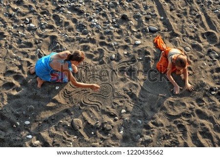 Girls paint in the sand.