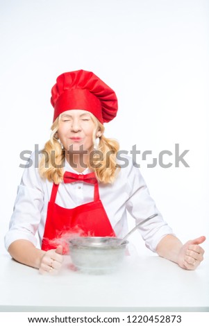Cook in a red apron and hood conducts experiments with liquid nitrogen on a white background