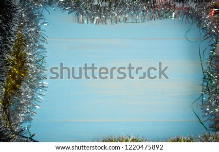Christmas decorations background with lights, snowflakes, tinsel and bells lie on wooden texture. Top view with empty space.