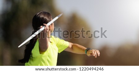 Female athlete throwing a javelin, rear view Royalty-Free Stock Photo #1220494246