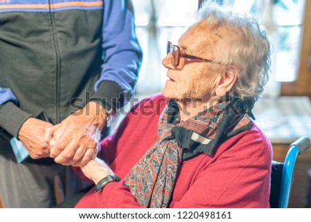 Ederly couple holding hands at home.