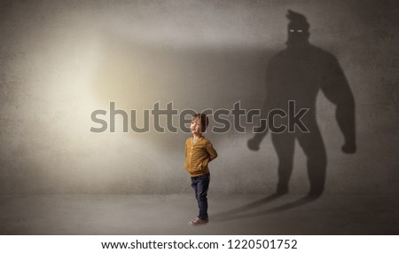 Cute kid in a room with plush on his hand and hero shadow on his background