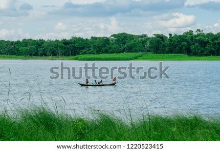 Passengers are crossing the river from on side to another side amidst the green nature