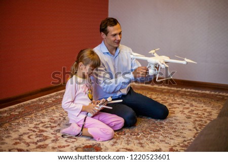 Dad with a child control copter. Dad teaches a child how to control a copter. Dad gave the child a gift copter.
