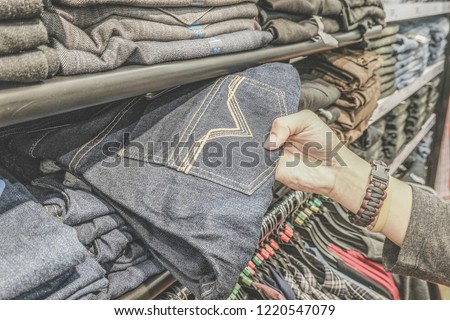 jeans store shopping. shelf with new blue jeans in store. Man hand check some jeans and choose some item. Shopping concept.